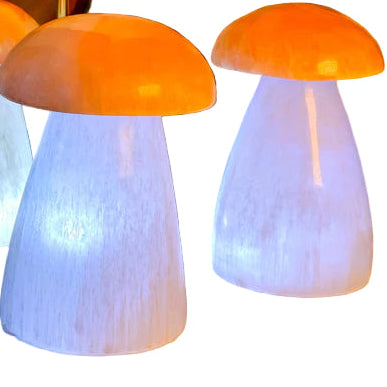 Four mushroom-shaped lamps with orange caps and white bases on a wooden surface.