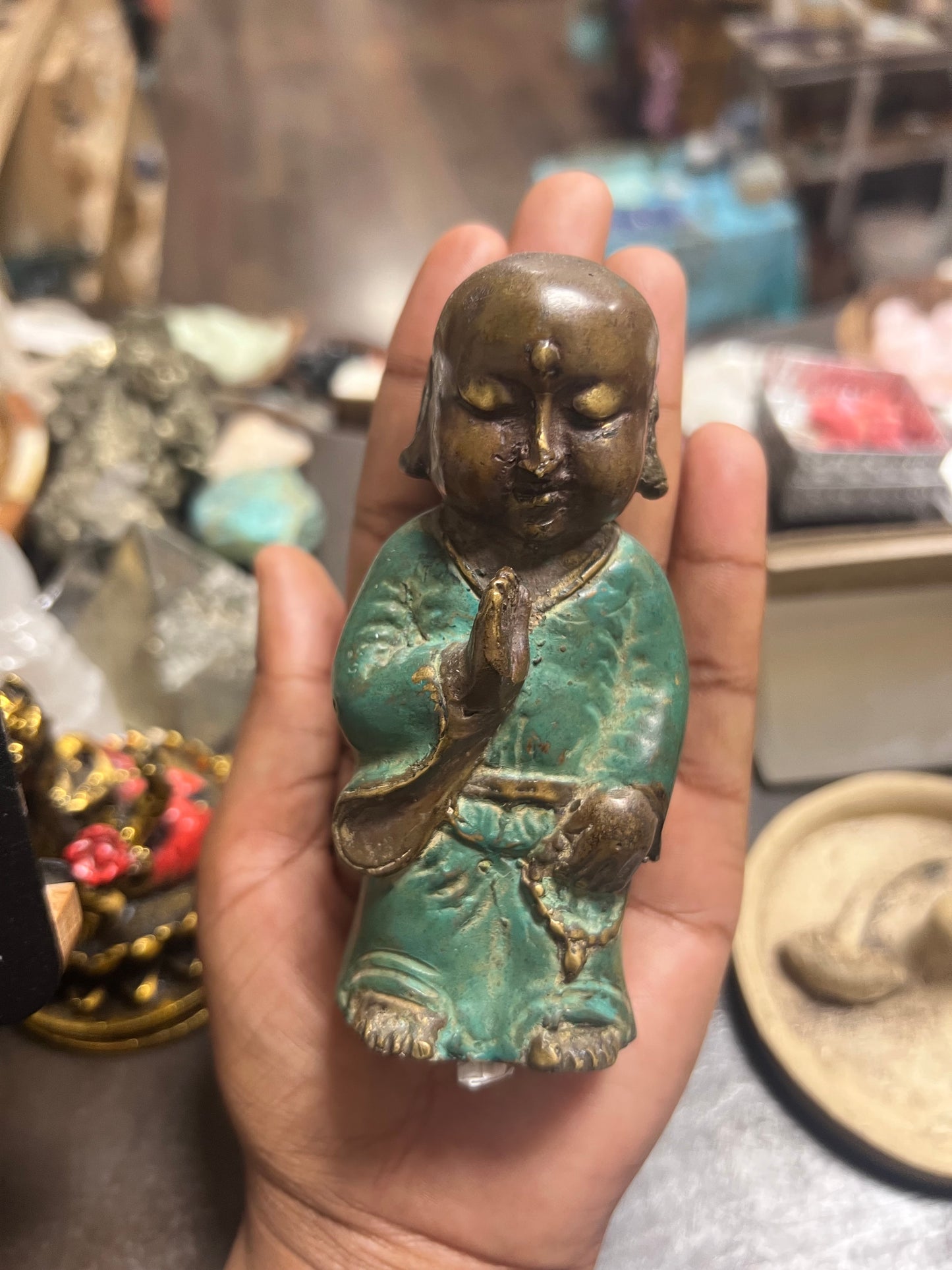 Hand holding a small statue of a seated figure with a blurred background