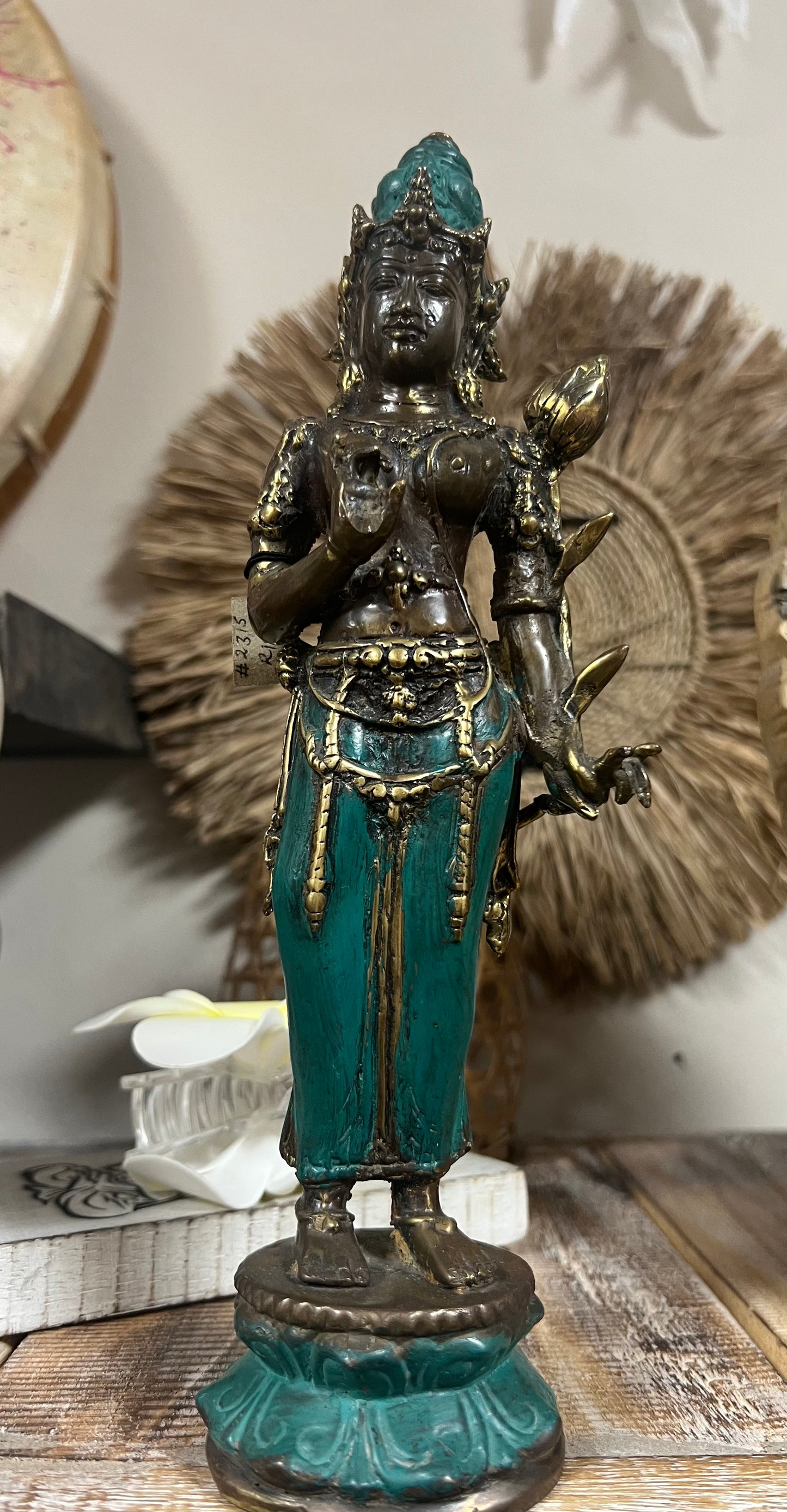 Decorative statue with teal and gold colors on a wooden surface.