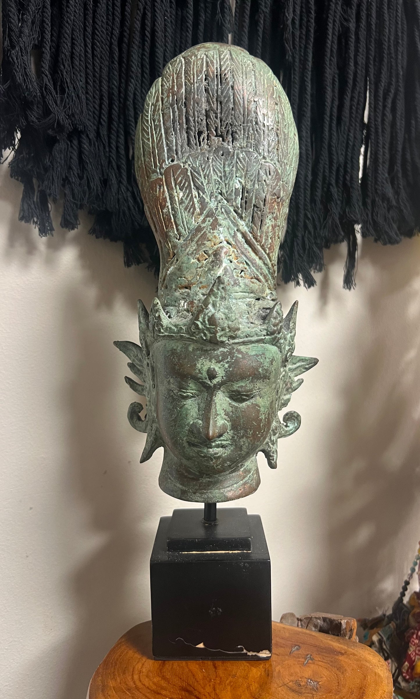 Bronze head sculpture on a stand against a neutral background