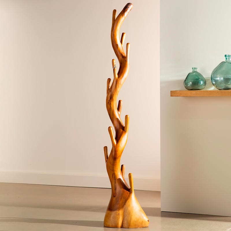 Wooden coat rack shaped like a tree branch against a plain wall.