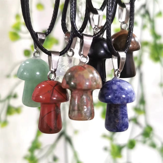 Colorful mushroom-shaped stone pendants on leather cords with a green leafy background.