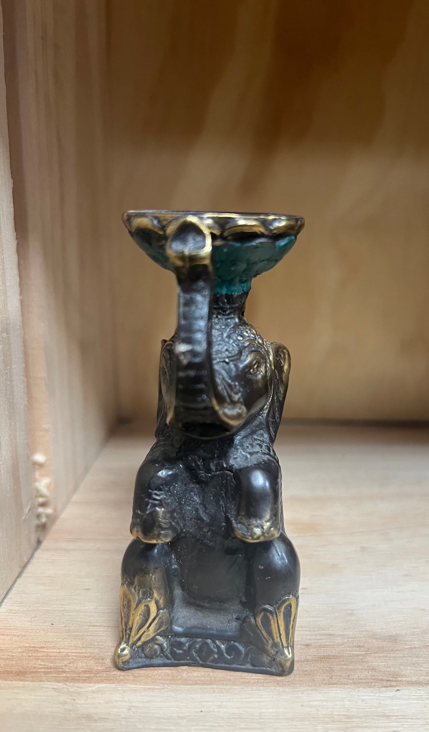 Brass elephant statue with a small bowl on a wooden surface