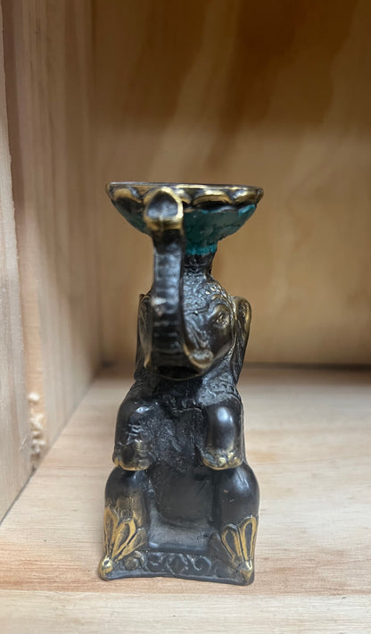 Brass elephant statue with a small bowl on a wooden surface