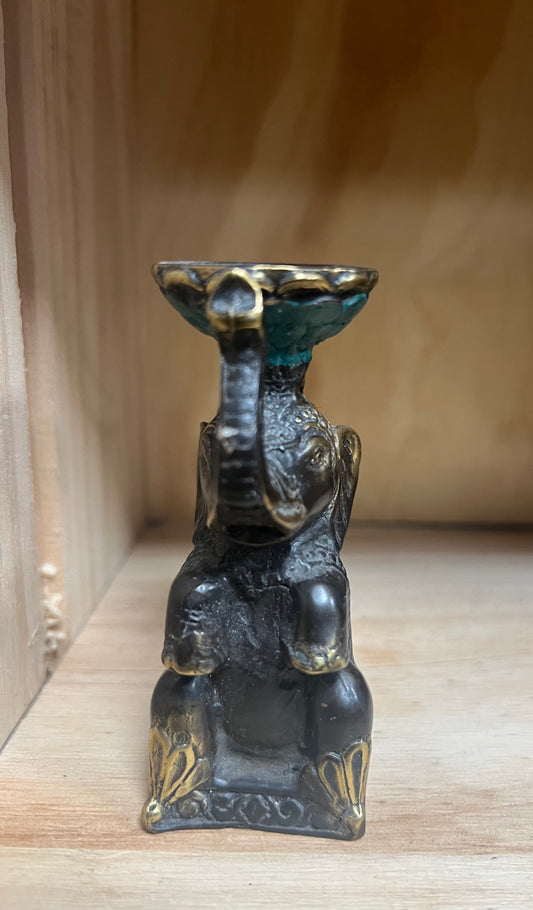 Brass elephant statue with a small bowl on a wooden surface