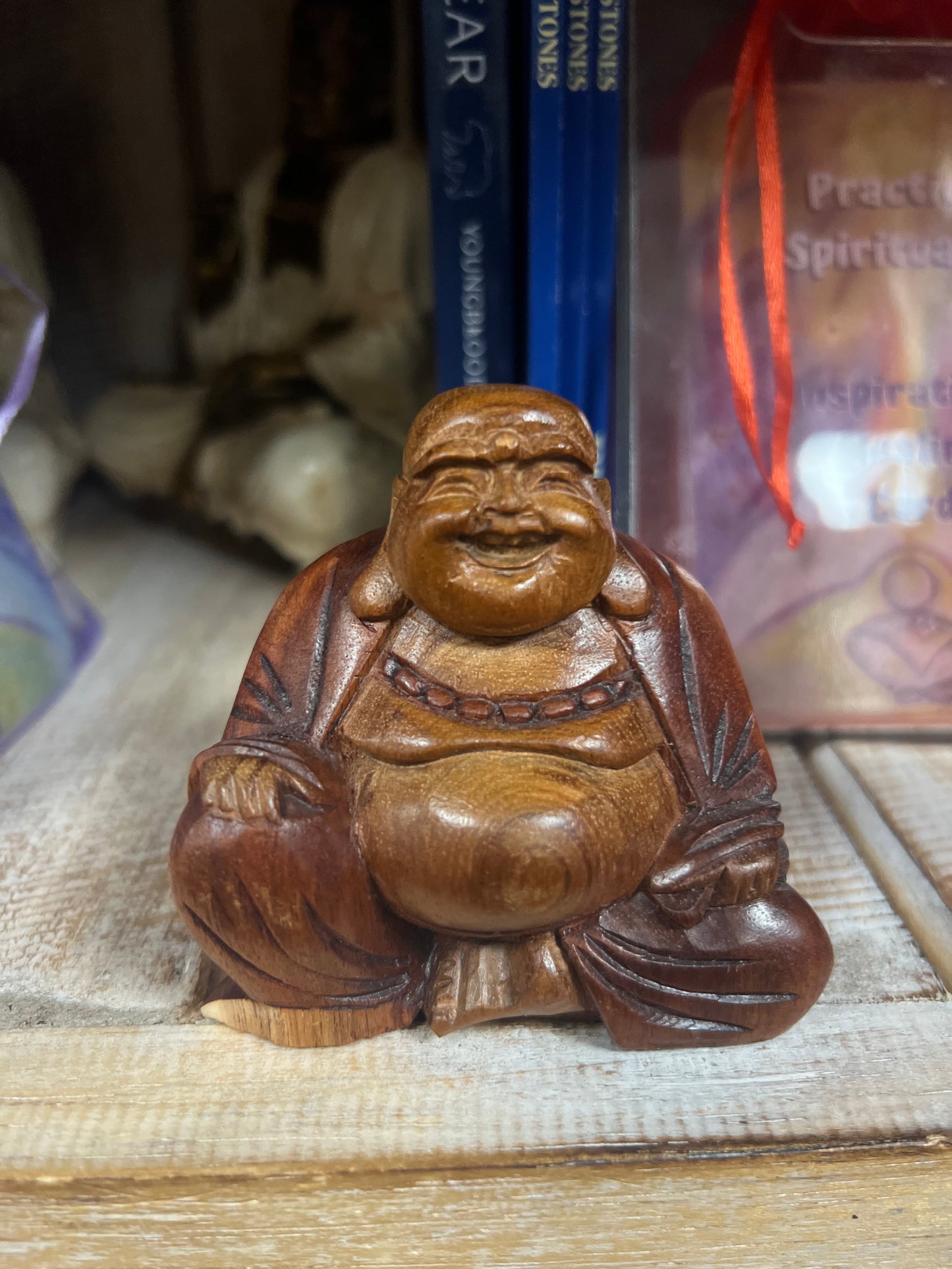 Wooden Buddha figurine on a textured surface with books in the background