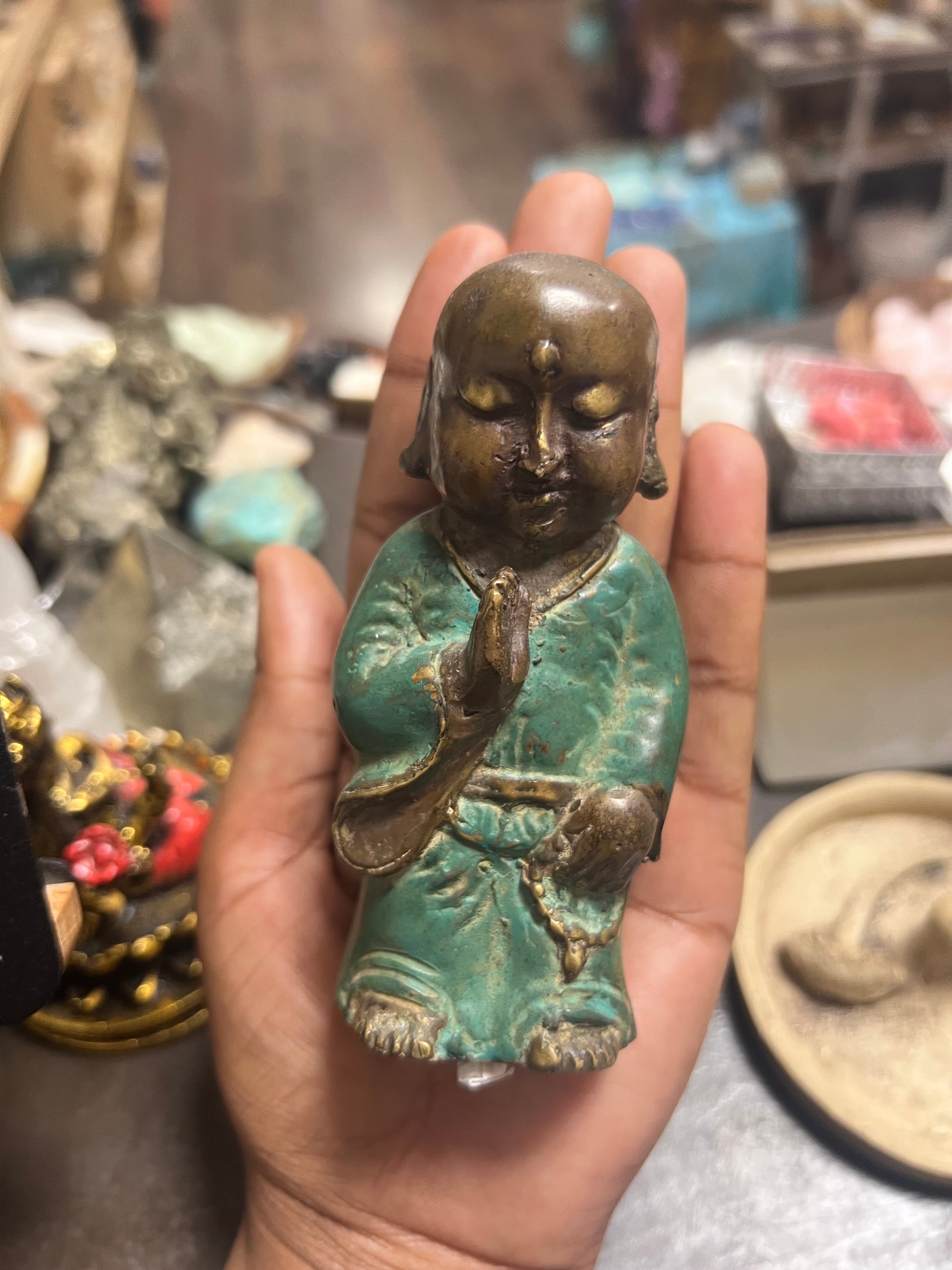 Hand holding a small statue of a seated figure with a blurred background