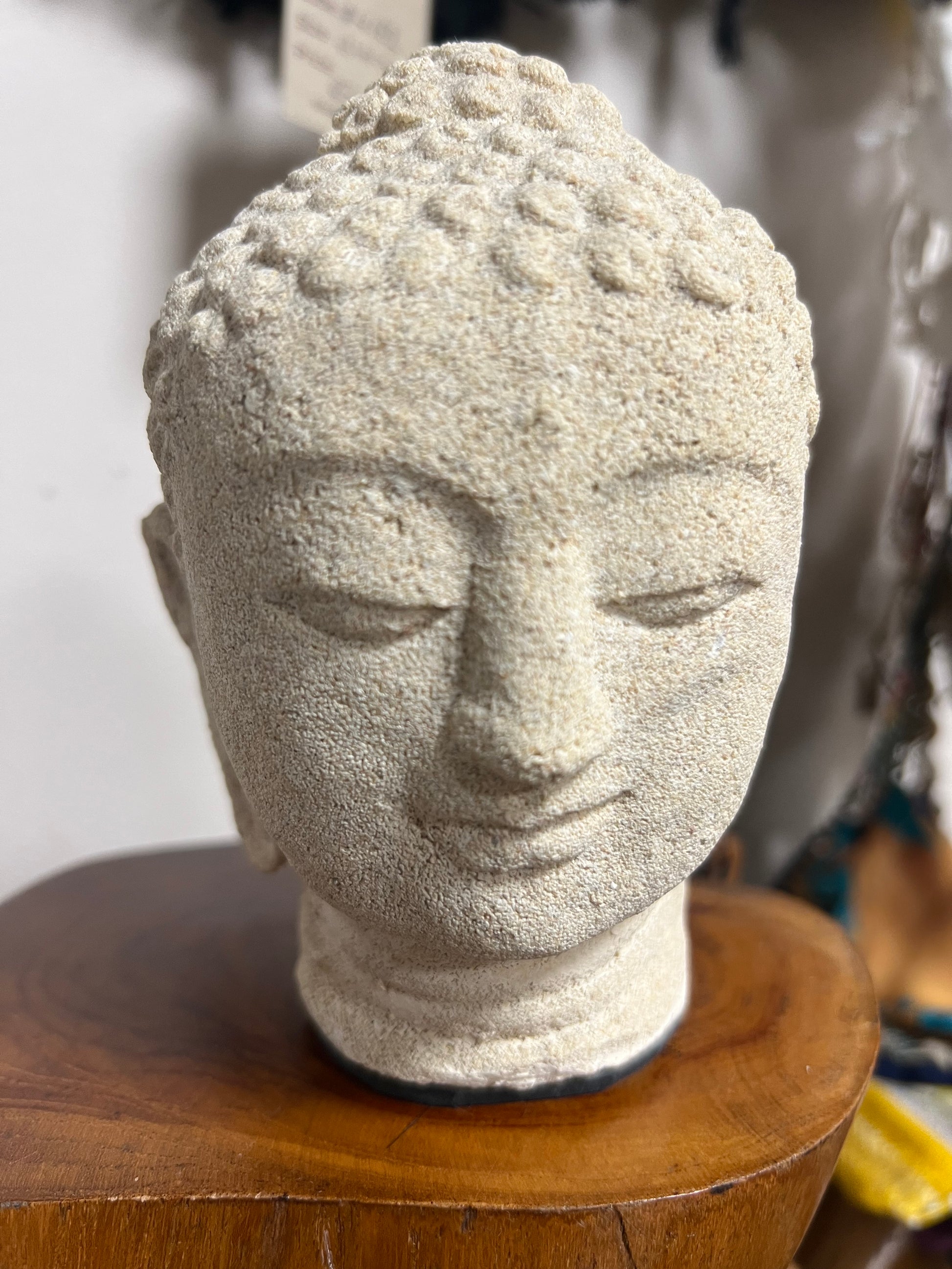 Stone sculpture of a face on a wooden base with a blurred background