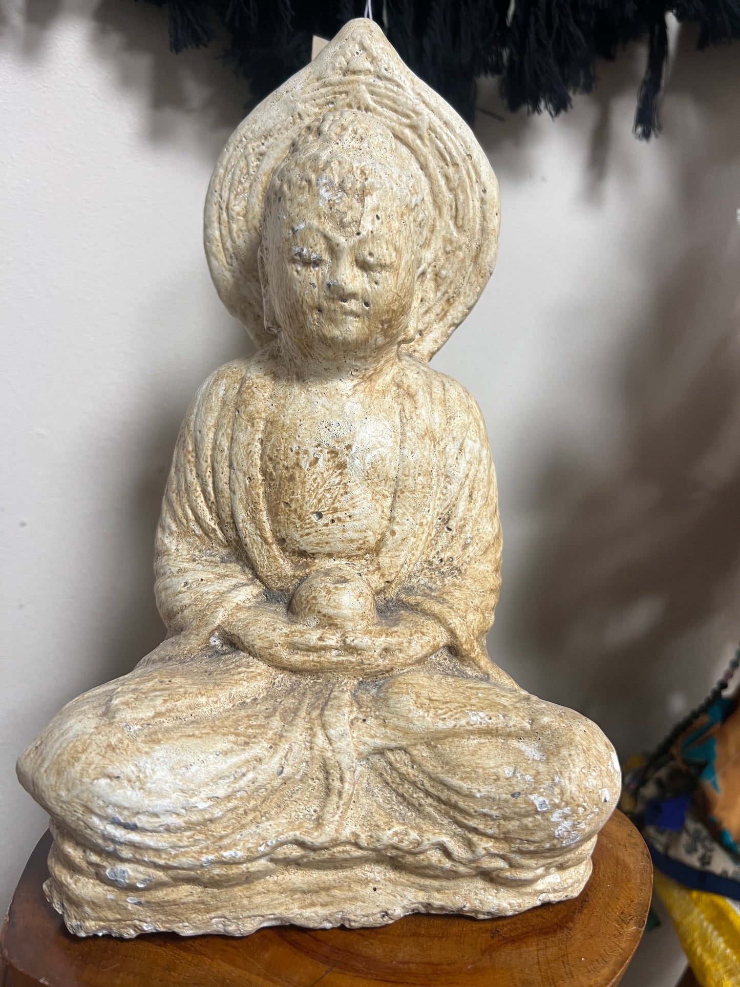 Decorative stone sculpture of a seated figure on a white surface
