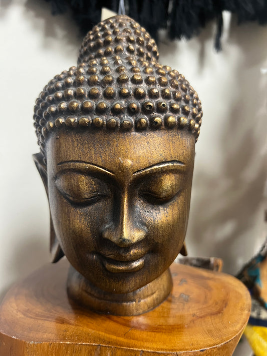 Bronze Buddha head sculpture on a wooden base