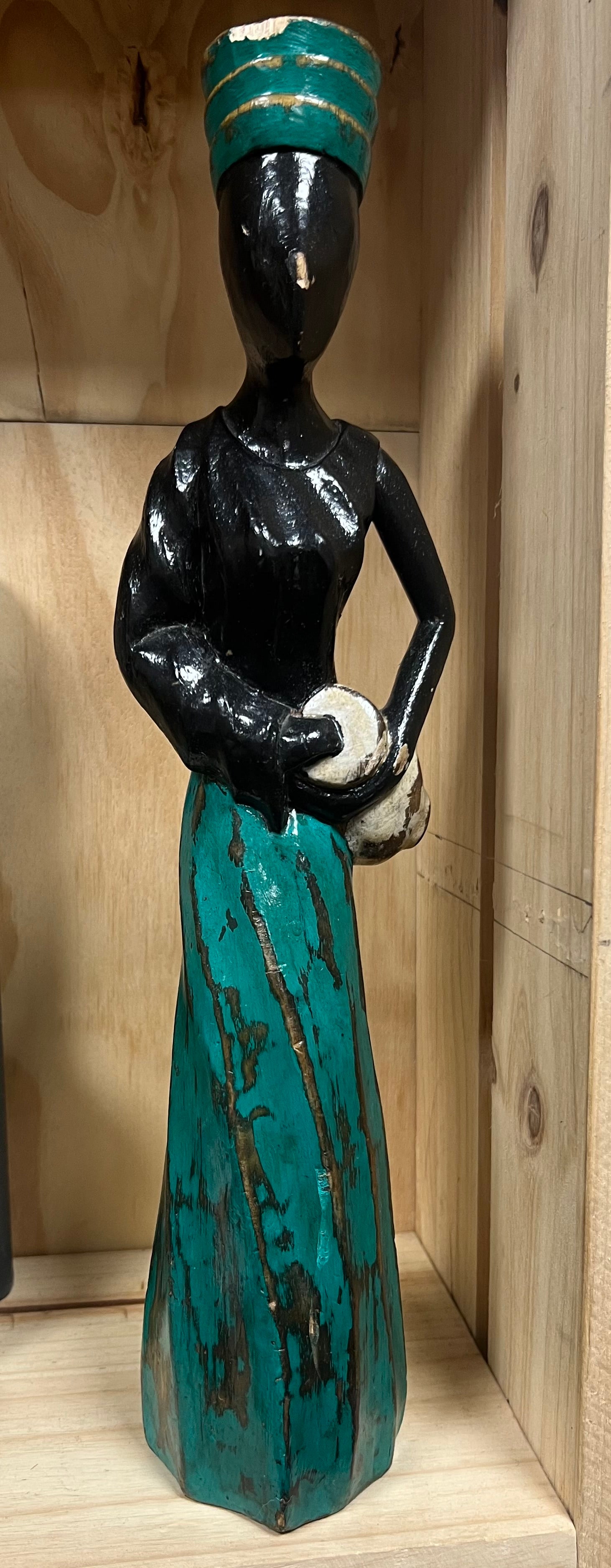 Decorative figure with teal and black attire on a wooden shelf