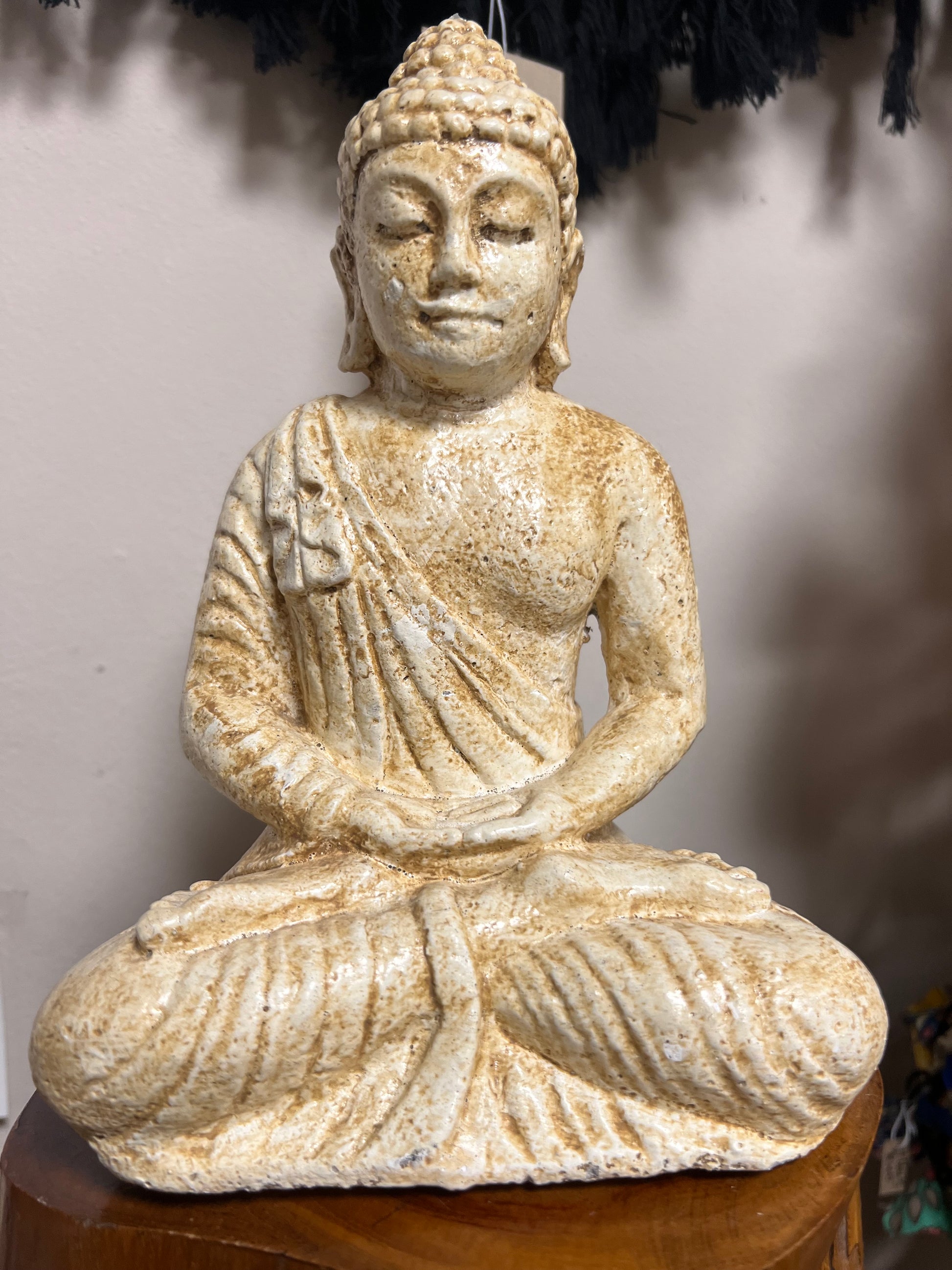 Statue of a seated figure with draped fabric on a plain background