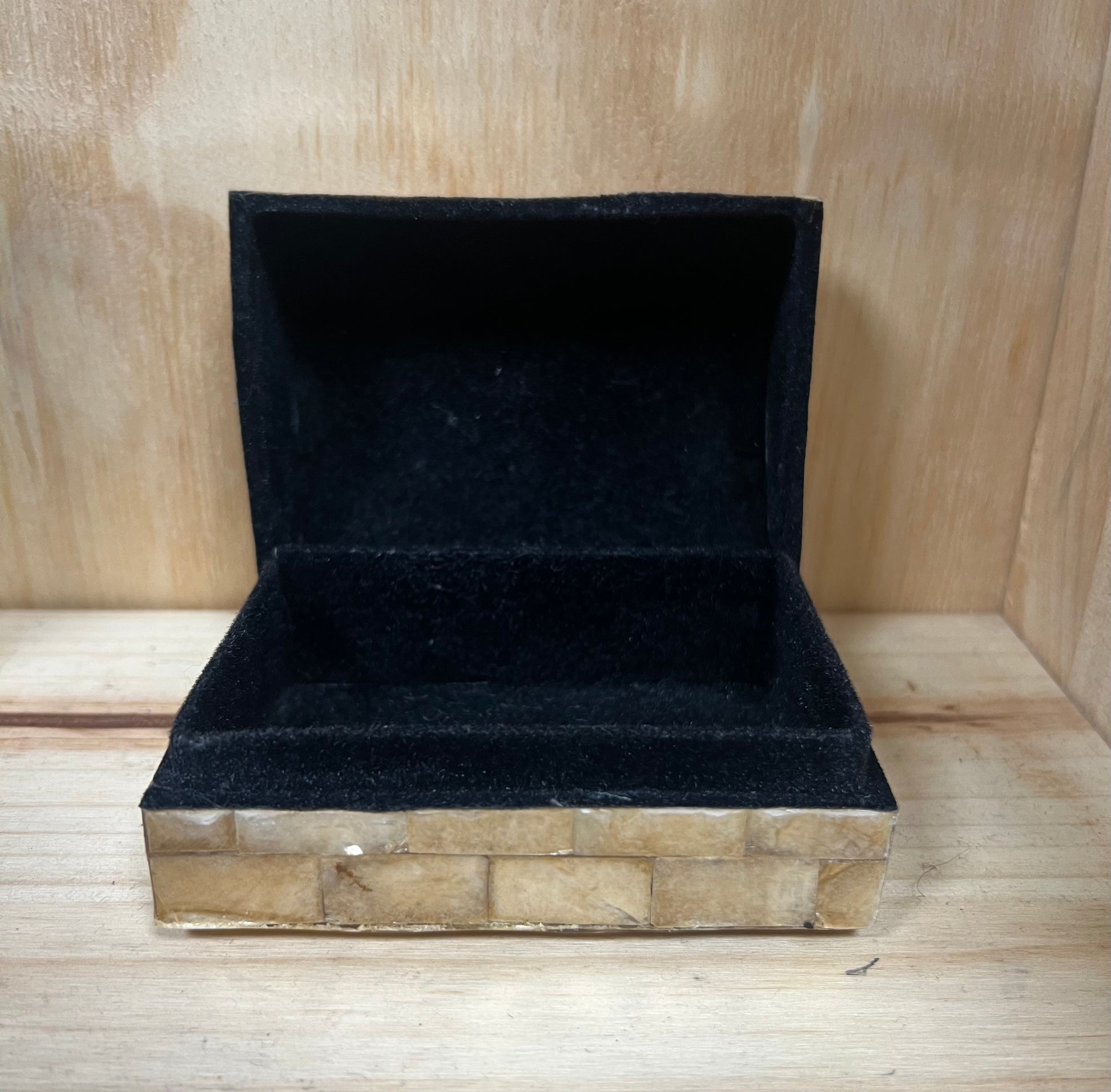 Black velvet jewelry box on a wooden surface