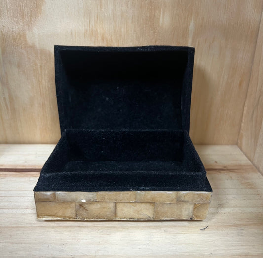 Black velvet jewelry box on a wooden surface
