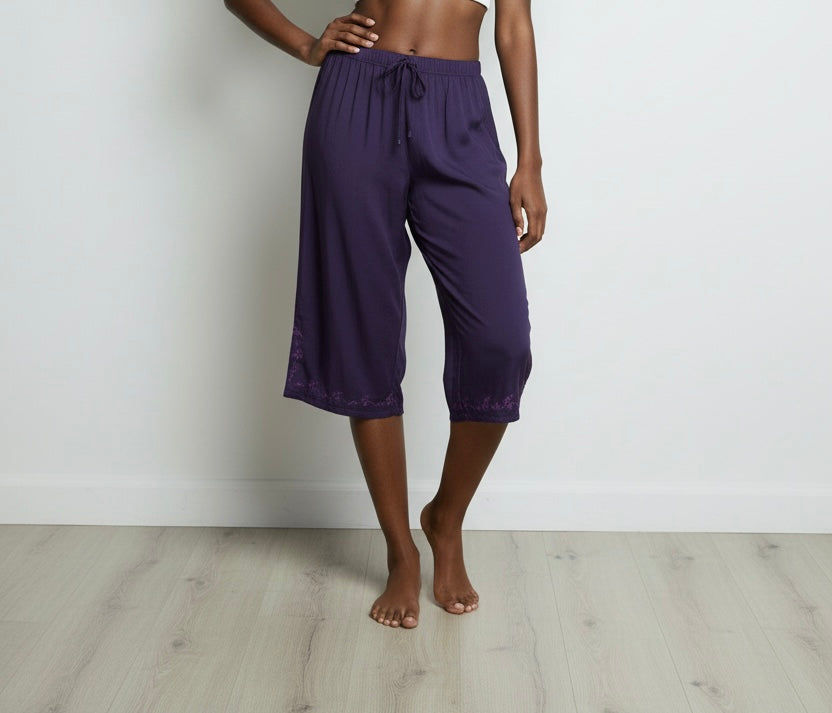 Person wearing purple capri pants on a plain background