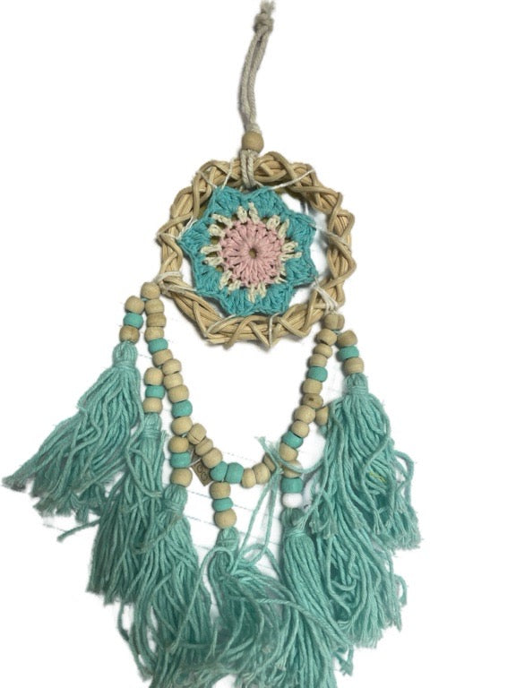 Decorative hanging ornament with teal tassels and a central flower design on a white background