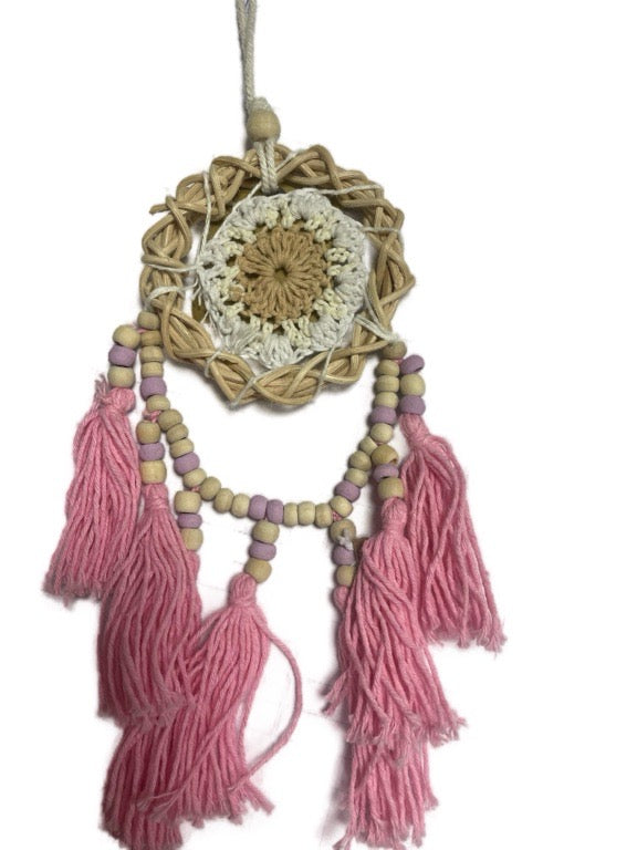 Decorative wall hanging with crochet design and pink tassels on a white background