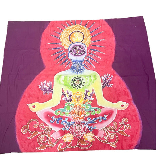 Colorful tapestry with a design of a sitting figure and chakra symbols on a purple background