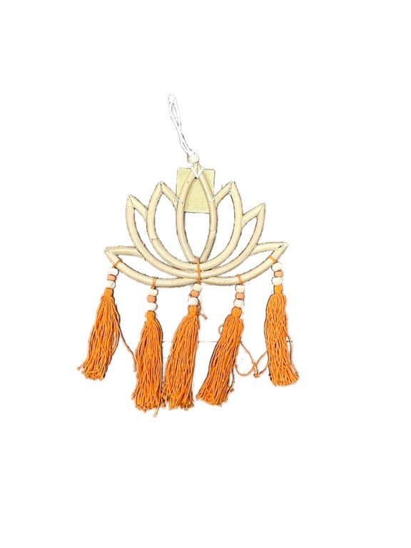 Decorative wall hanging with a lotus flower design and orange tassels on a white background