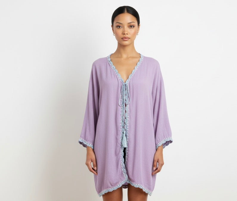 Woman wearing a light purple cover-up with lace trim on a plain background